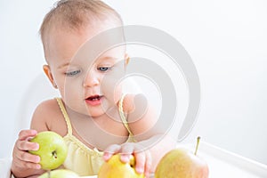 cute baby girl in baby chair eating apples. Baby first solid food