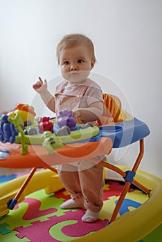 Cute baby girl in baby walker at home