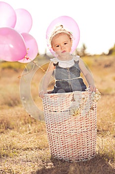 Cute baby girl with balloons outdoors