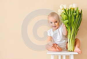 Cute baby girl with a bouquet of spring tulips. A gift for the mother`s Day holiday, a spring concept