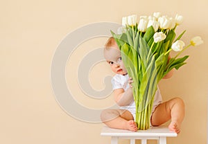 Cute baby girl with a bouquet of spring tulips. A gift for the mother`s Day holiday, a spring concept