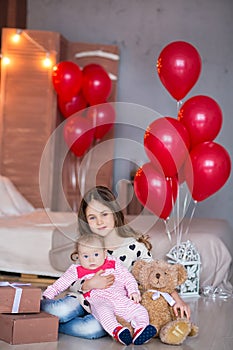 Cute baby girl celebrating birth day together close to red balloons.Lovely scene of baby on sofa divan with presents and