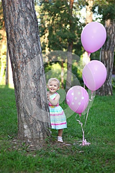 Cute baby girl in a colorful dress smiling in the park