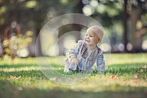 Cute baby girl crawling on lawn in park