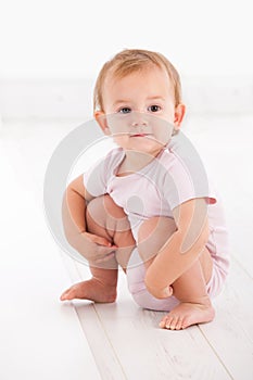 Cute baby girl crouching on floor photo