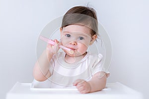 Cute Baby girl eating blend mashed food sitting, on high chair, mother feeding child, hand with spoon for vegetable