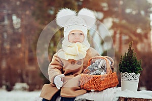 Cute baby girl enjoying winter walk in snowy park, wearing warm hat