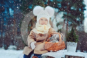 Cute baby girl enjoying winter walk in snowy park, wearing warm hat