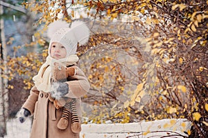 Cute baby girl enjoying winter walk in snowy park, wearing warm hat
