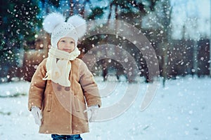 Cute baby girl enjoying winter walk in snowy park, wearing warm hat