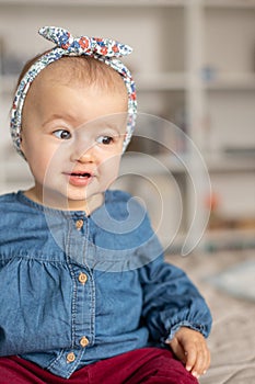 Cute baby girl with hairband ribbon, smilling. Adorable child at home