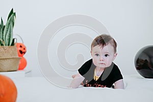 Cute baby girl in halloween costume at home, sitting on bed with Halloween decoration, Lifestyle indoors