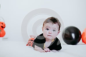 Cute baby girl in halloween costume at home, sitting on bed with Halloween decoration, Lifestyle indoors