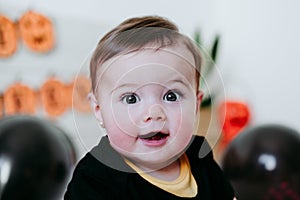 Cute baby girl in halloween costume at home, sitting on bed with Halloween decoration, Lifestyle indoors