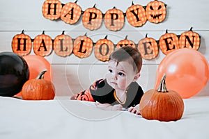 Cute baby girl in halloween costume at home, sitting on bed with Halloween decoration, Lifestyle indoors
