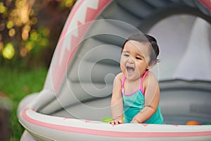 Cute baby girl having fun in inflatable pool