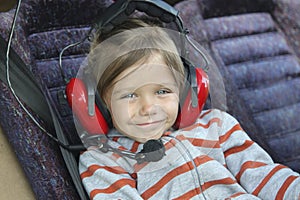 cute baby girl in headphones sitting in the cockpit of a small t