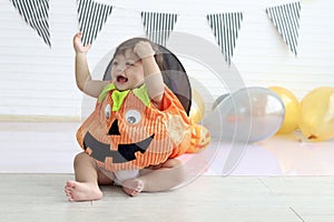 Cute baby girl kid dressing up in orange fancy Halloween pumpkin costume, cheerful little cute child wearing black witch hat ready