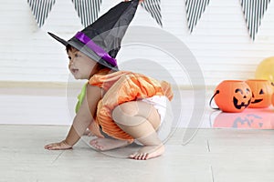 Cute baby girl kid dressing up in orange fancy Halloween pumpkin costume, cheerful little cute child wearing black witch hat ready