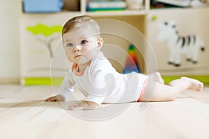 Cute baby girl learning crawling and sitting in children room