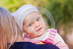 Cute baby girl looking out from mother's back