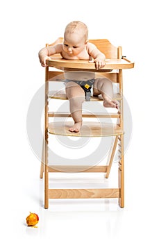 Cute baby girl looking at peach she dropped while sitting in high chair