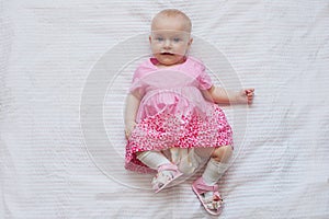 Cute baby girl in pink dress lies on white backgroun. Newborn child