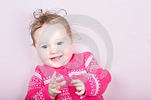 Cute baby girl in a pink knitted sweater with hearts pattern