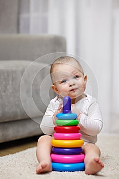Cute baby girl playing with colorful toy pyramid