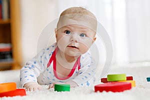 Cute baby girl playing with colorful wooden rattle toy