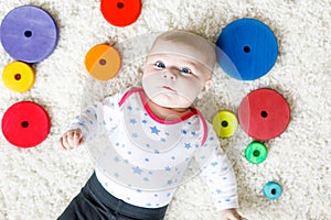 Cute baby girl playing with colorful wooden rattle toy