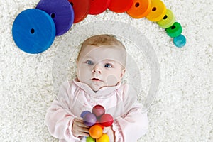 Cute baby girl playing with colorful wooden rattle toy