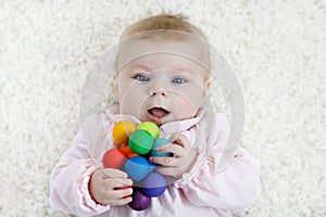 Cute baby girl playing with colorful wooden rattle toy