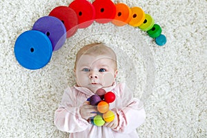 Cute baby girl playing with colorful wooden rattle toy