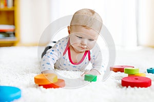 Cute baby girl playing with colorful wooden rattle toy