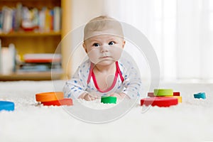 Cute baby girl playing with colorful wooden rattle toy