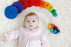 Cute baby girl playing with colorful wooden rattle toy