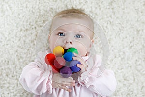 Cute baby girl playing with colorful wooden rattle toy