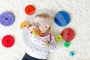 Cute baby girl playing with colorful wooden rattle toy