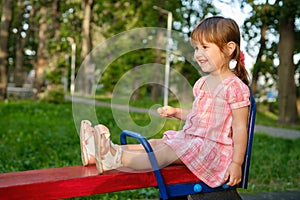 Cute baby girl Playing At Playground In Summer Sunny Day. Little girl licking chupa chups