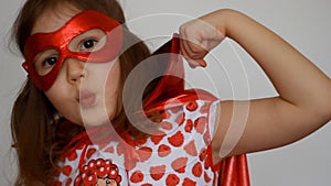 Cute baby girl plays superhero. Funny child in a red raincoat and mask playing power super hero. Superhero and power