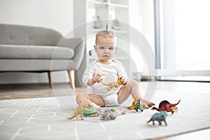 Cute baby girl posing with toy animals on floor indoors