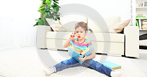 Cute baby girl reading book at home sitting on floor