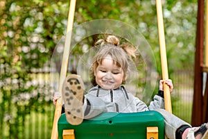 Cute baby girl on a seesaw swing at the playground.Cute baby girl on a swing seesaw. on the playground in the park