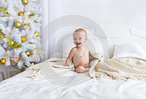 Cute baby girl sitting on bed at bedroom. Christmas.