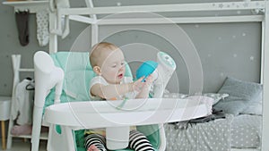 Cute baby girl sitting on highchair licking plate