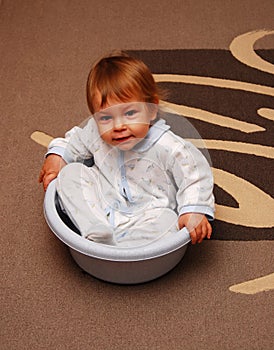 Cute baby girl sitting in pan