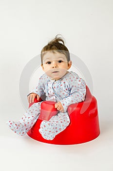 Cute baby girl sitting in a plastic seat