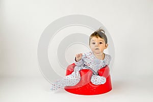 Cute baby girl sitting in a plastic seat