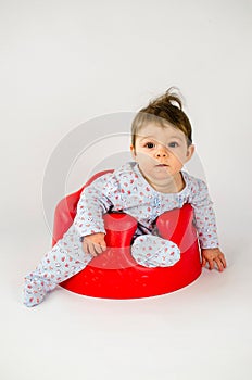 Cute baby girl sitting in a plastic seat